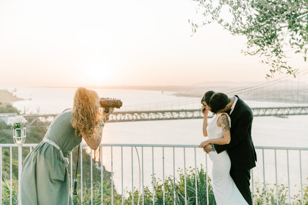 a lisbon wedding photographer photographing a bride and groom on their wedding day with a beautiful view over 25 de Abril bridge in Lisbon